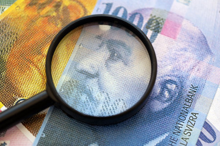 Swiss franc banknotes and magnifying glass. The current francs money bills with loupe lies on table in big amount. The concept of financial monitoring and taxation in Switzerlandの写真素材