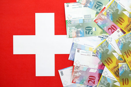 Swiss franc banknotes and flag. The current francs money bills lies on flag in big amount. The...