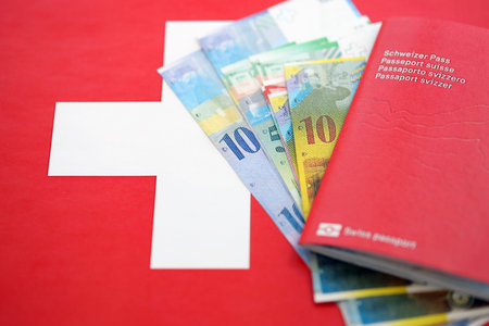 Swiss franc banknotes and passport with tickets on flag. The current francs money bills and biometrical pass lies on flag. The concept of travel and vacation in Switzerlandの写真素材