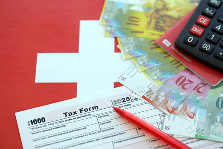 Swiss franc banknotes and tax form on flag. The current francs money bills lies on tax form and flag. The concept of taxation in Switzerlandの写真素材