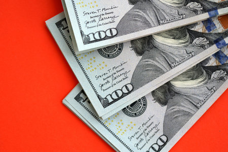 Big amount of United States hundred dollar bills on red background. Concept of taxation and money makingの写真素材