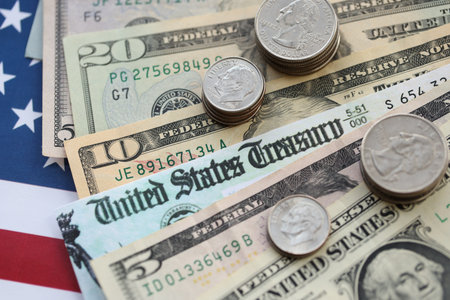 American US dollars money bills and coins with stimulus bill or refund check on American flag close...