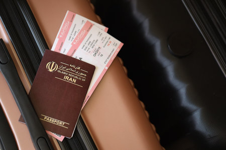 Islamic Republic of Iran passport with tickets lies on touristic suitcase close up in airport waiting hall. Travel worldwide and international tourism conceptの写真素材