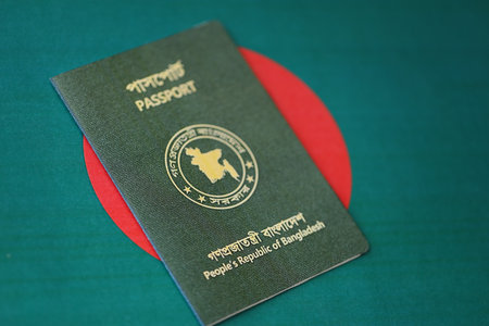 Bangladeshi passport lies on Bangladesh flag close up. Travel and citizenship conceptの写真素材