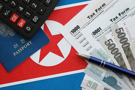 North Korean won money bills in big amount lies on table with pen, calculator, passport and tax forms close up. Taxpaying and accounting conceptの写真素材