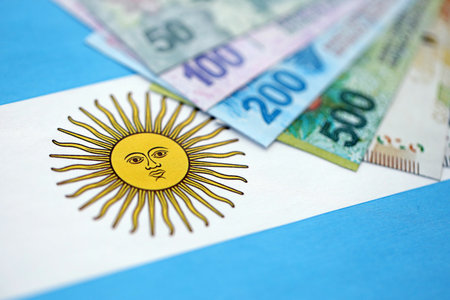 Argentine pesos money bills in big amount lies on Argentina flag close up. Finance and banking conceptの写真素材