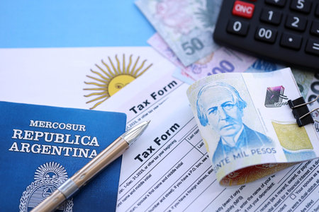 Argentine pesos money bills in big amount lies on table with pen, calculator, passport and tax forms close up. Finance and banking conceptの写真素材