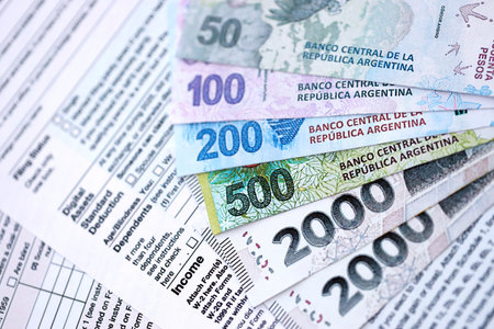 Argentine pesos money bills in big amount lies on table with pen and tax forms close up. Finance and banking conceptの写真素材