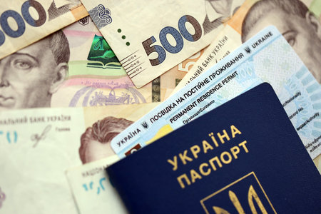 Ukrainian residence permit card or permanent resident card with passport on Ukrainian money close up