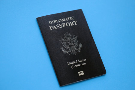 United States diplomatic passport book on light blue paper background close up. Travel document on...
