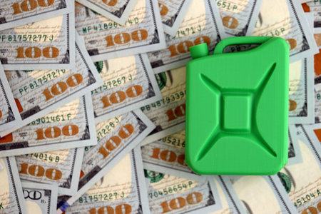 Petroleum or gasoline canister reservoir lies on big amount of dollar bills. Concept of petrol prices in United Statesの写真素材