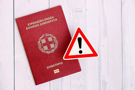 Greece passport with exclamation sign on white wooden background close up. Problems with citizenship in Europe conceptの写真素材