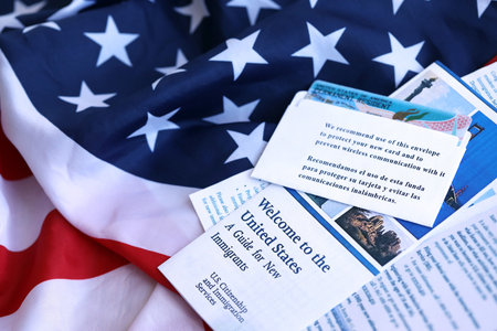 Permanent resident green card in envelope and guide for new immigrants lies on US flag close upの写真素材
