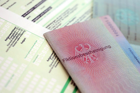 German temporary Permanent resident card specimen lies on german tax form close up. Fiktionsbescheinigung and einkommensteuererklarungの写真素材