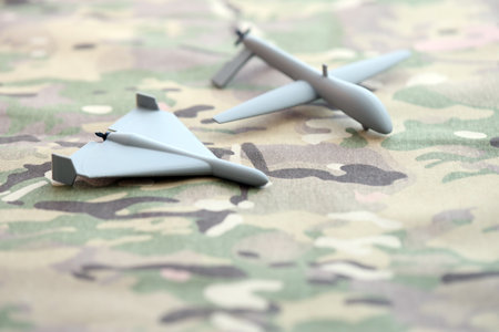 Unnamed grey toy drones models on camouflage fabric close up.の写真素材
