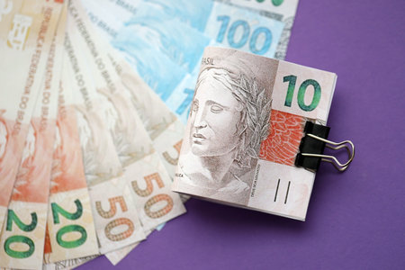 Close up of brazilian reais money bills in big amount on purple table. Pile of Brazil real currency...