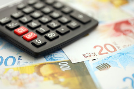 Israel New Shekels banknotes and calculator. The current Israel money bills and calc lies on table in big amount. The concept of taxation and money count in Israelの写真素材