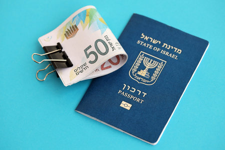 Israel New Shekels banknotes and passport on blue background. The current Israel money bills lies on blue in big amount. The concept of finances and cash in Israelの写真素材