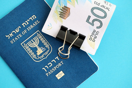 Israel New Shekels banknotes and passport on blue background. The current Israel money bills lies on...