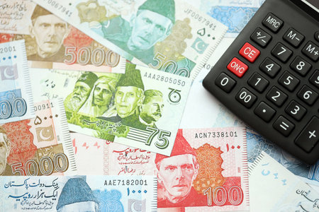 Pakistan rupees banknotes and calculator. The current Pakistan money bills and calculator lies on table in big amount. The concept of taxation and money count in Pakistanの写真素材