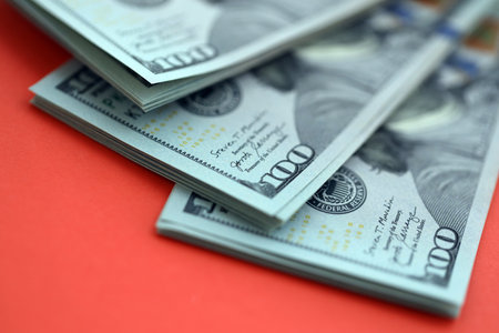 Big amount of United States hundred dollar bills on red background. Concept of taxation and money making in United Statesの写真素材