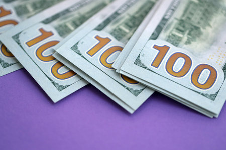 Big amount of United States hundred dollar bills on purple background. Concept of taxation and money making in United Statesの写真素材