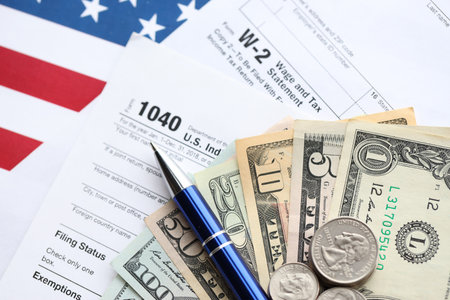 American US dollars money bills and coins with pen on IRS tax form blanks close up. Accounting and taxpaying period conceptの写真素材