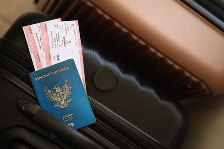 Indonesian passport with tickets lies on touristic suitcase close up in airport waiting hall. Travel...