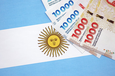 Argentine pesos money bills in big amount lies on Argentina flag close up. Finance and banking conceptの写真素材