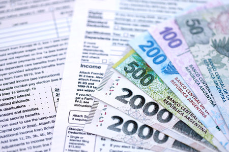 Argentine pesos money bills in big amount lies on table with pen and tax forms close up. Finance and banking conceptの写真素材