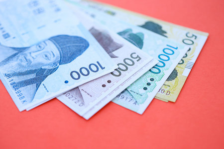 South Korean won money bills in big amount lies on red color table close up. Finance and banking...