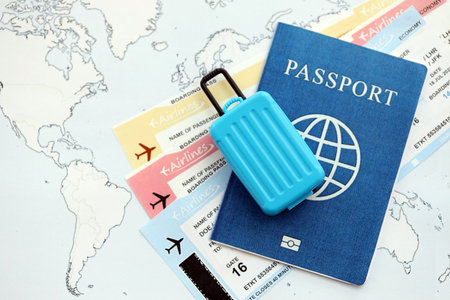 Passport with boarding pass tickets and toy luggage bag on world map close upの写真素材