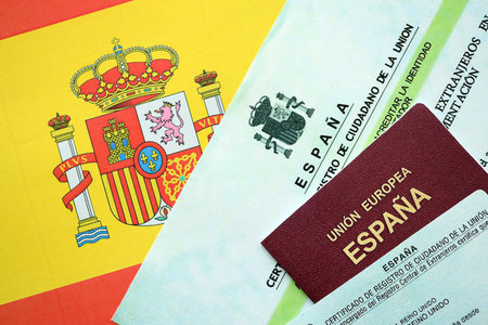 Spanish passport lies on citizenship or naturalization documents on flag of Spain close upの写真素材