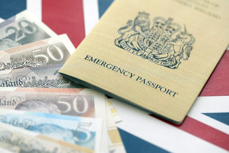 British emergency passport. Yellow color temporary document with british money on flag background close upの写真素材
