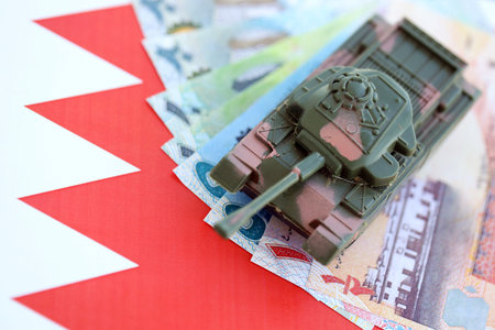 Bahraini dinar currency money bills and toy tank on flag close up.の写真素材
