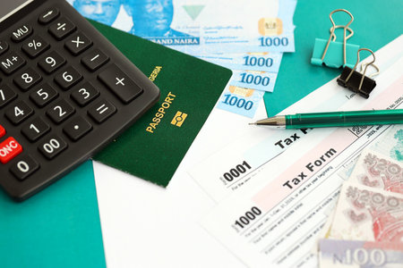 Nigerian naira money bills and calculator with tax form on flag close up. Taxation and accounting conceptの写真素材