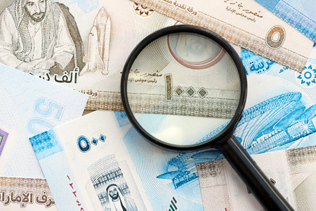 United Arab Emirates dirham currency money bills and magnifying glass close up. The concept of...