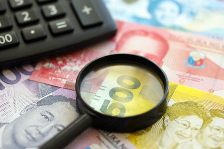 Philippines peso currency money bills and calculator with magnifying glass close up. The concept of taxation and money countの写真素材