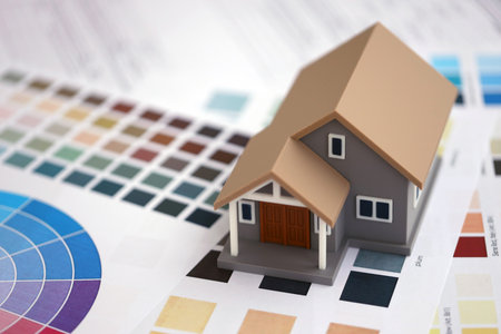 Small toy house and papers with color palette samples. Concept of interior and exterior design and...