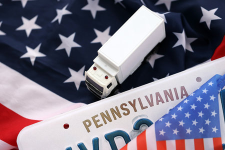 Toy truck and USA state of Pennsylvania license plate on US flag. Concept of driving in Pennsylvania. Reaching a driving permitの写真素材