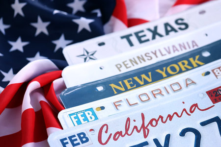 Old US car license plates with various state names on USA flag. Concept of driving in United States. Reaching a car registrationの写真素材
