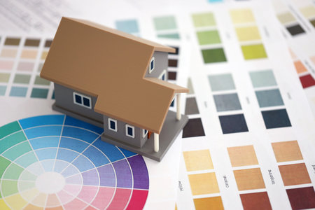Small toy house and papers with color palette samples. Concept of interior and exterior design and...