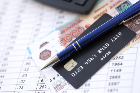 Credit card and pen with russian ruble currency money bills banknotes on calculations document background. Business, financial operations and accounting in Russian Federationの写真素材