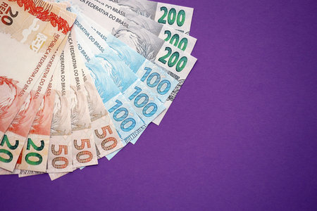 Close up of brazilian reais money bills in big amount on purple table. Pile of Brazil real currency banknotes. Finance and banking conceptの写真素材
