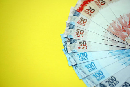 Close up of brazilian reais money bills in big amount on yellow table. Pile of Brazil real currency banknotes. Finance and banking conceptの写真素材