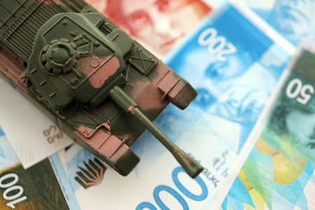 Israel New Shekels banknotes and toy tank. The current Israel money bills and tank lies on table in big amount. The concept of army funds and weapons sales in Israelの写真素材