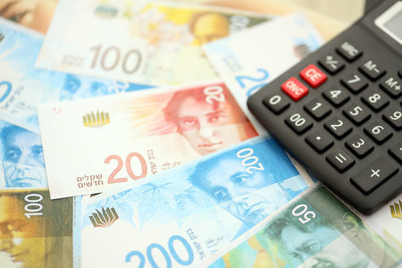 Israel New Shekels banknotes and calculator. The current Israel money bills and calc lies on table in big amount. The concept of taxation and money count in Israelの写真素材