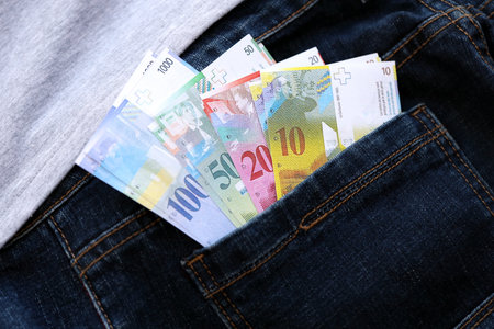 Swiss franc banknotes in denims pocket. The current francs money bills lies in jeans pocket. The concept of fashion and wealth in Switzerlandの写真素材