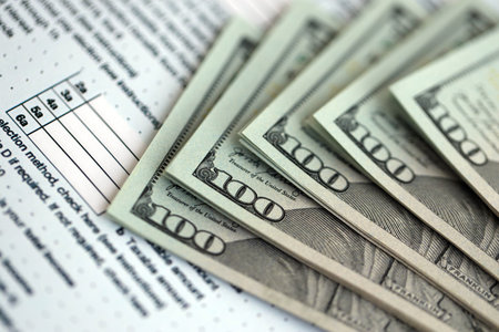 Big amount of United States dollar bills on table with individual income tax return form close up. Concept of taxation and accounting in United Statesの写真素材