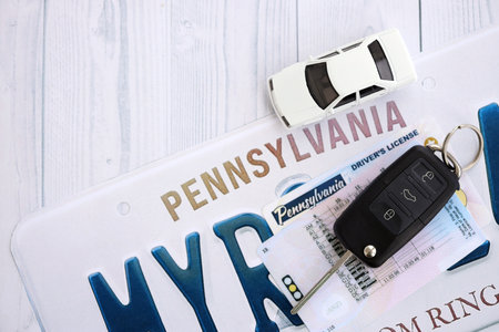 Remote control car keys on Pennsylvania license plate with driver license. Concept of driving in Pennsylvania. Reaching a driving permitの写真素材